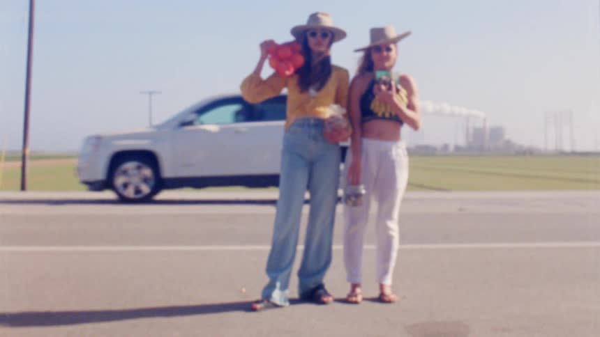 Two women standing on the side of a road