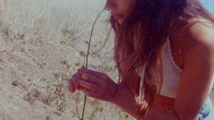 A woman leans down to smell flowers