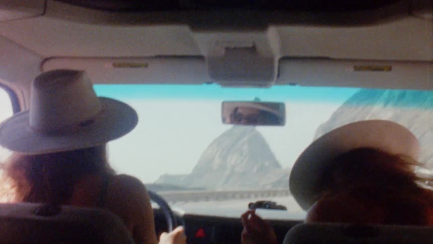 Two women are driving in a car near mountains