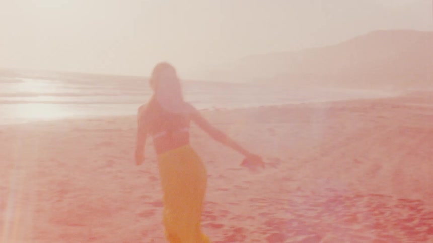 A woman is stretching her arms out and running on a sandy ocean beach