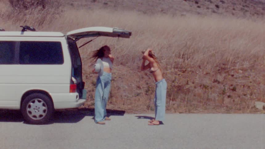 Woman stand near vehicle with open hatch backed with grass covered slope