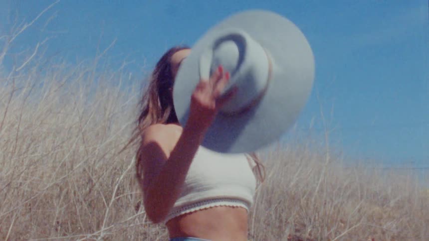 A woman takes off her hat and shakes her head around and then puts her hat back on