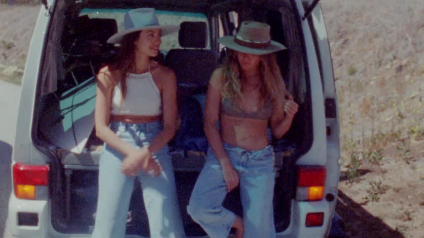 Women lean back against open vehicle with open hatchback