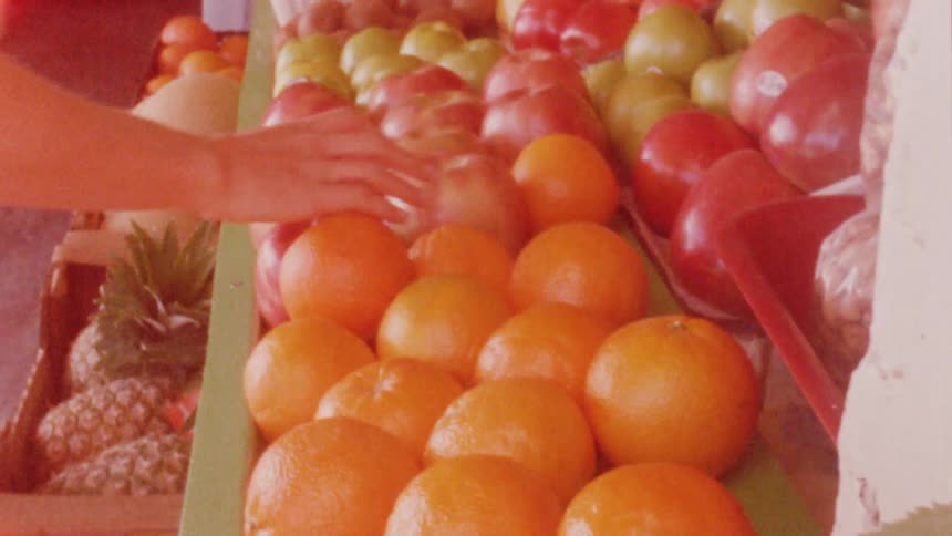 A person is touching the fruit in the store
