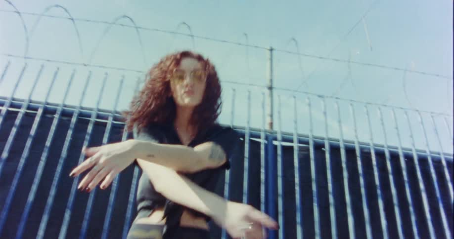 A woman is dancing by the large fence