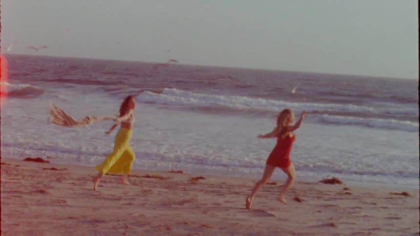 Two women running towards the ocean at the beach