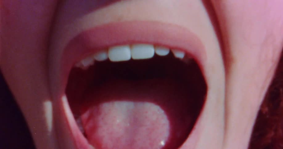 A woman opens her mouth wide and the camera zooms inside