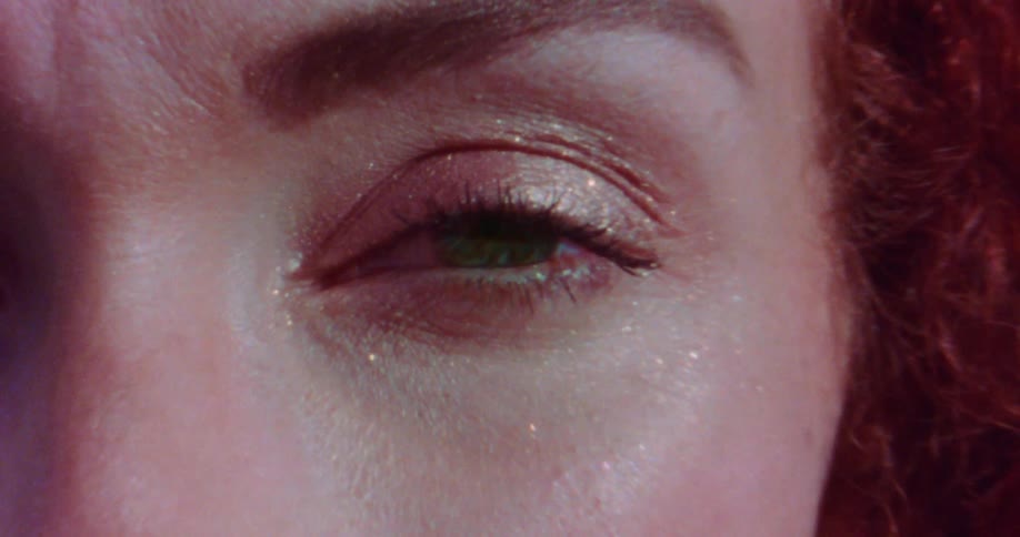 A woman wiggles her eyebrows as the camera gets closer to her face shimmering in the sunlight