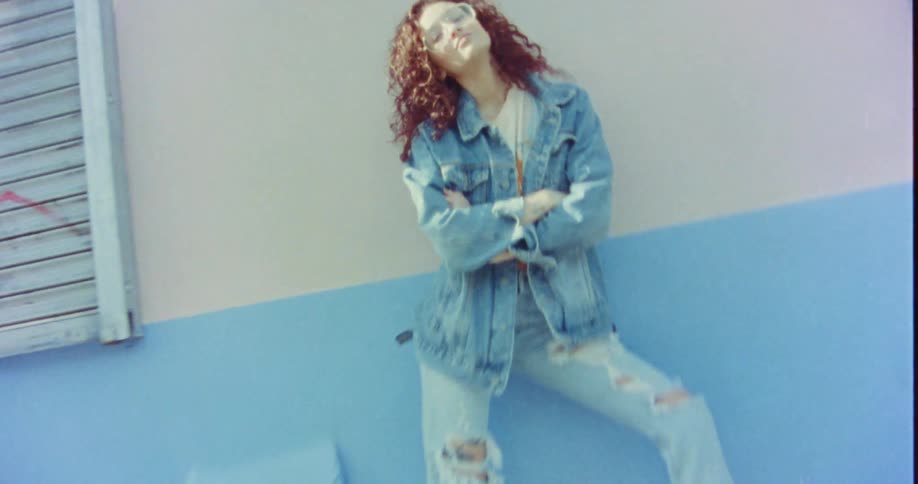 A female model is posing outdoors next to a building