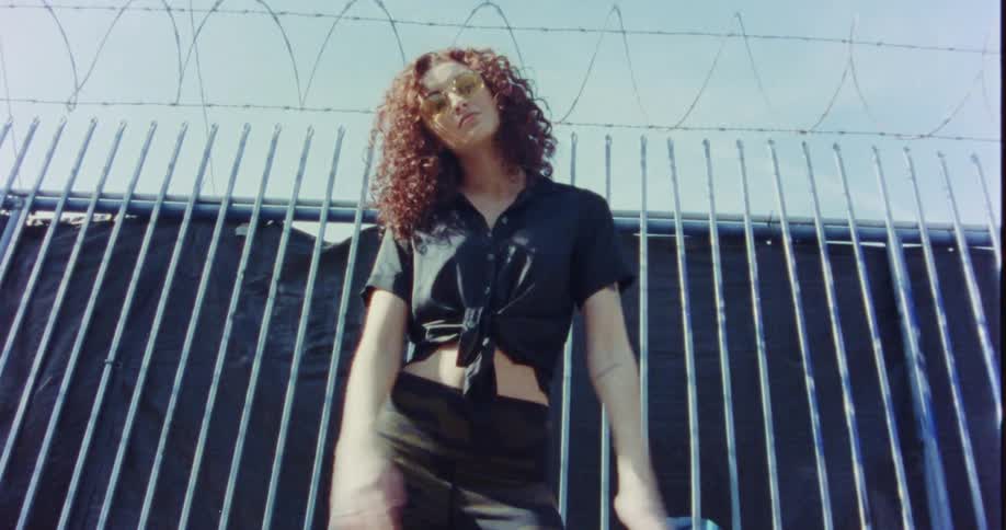 Woman sways and moves near razor wire topped fence