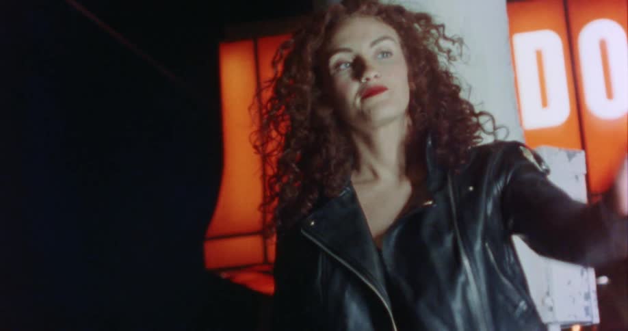 A woman is standing outdoors at night and smoking