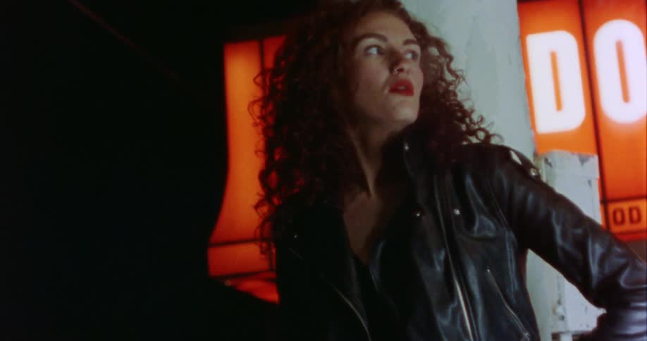 A woman is standing outdoors at night and smoking