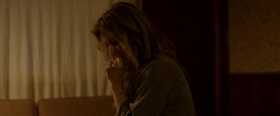 Blonde sad tired woman standing inside a dimly lit room at home