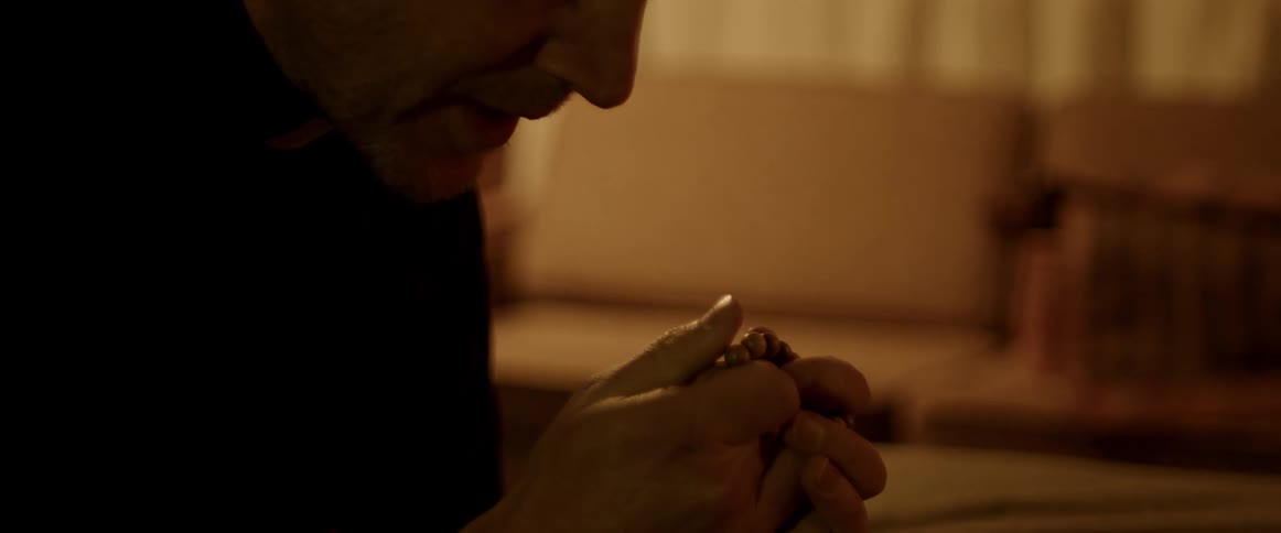 Man prays with bowed head as he fingers prayer beads