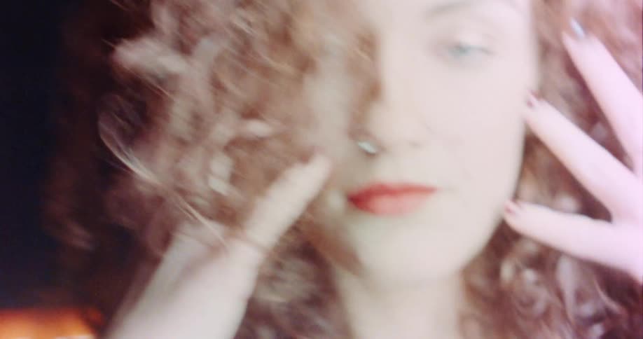 A woman is outside at night and holding her fingertips against her cheeks