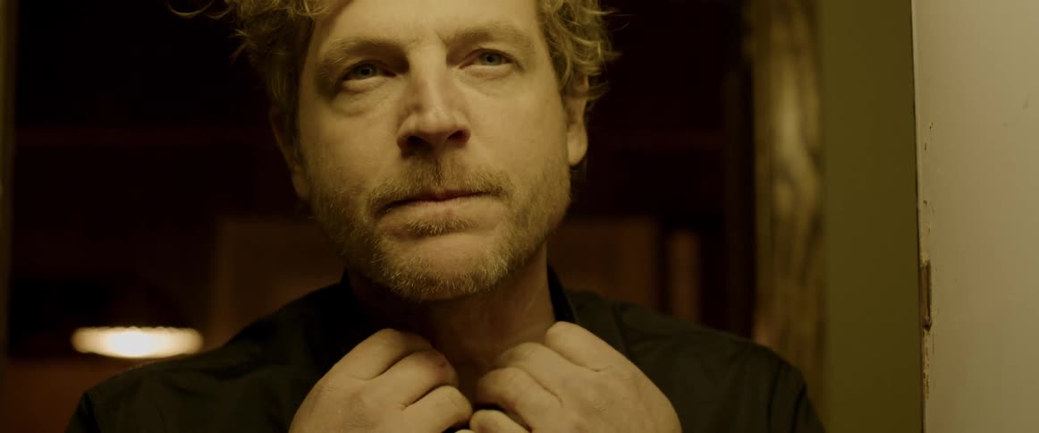 Close up of a man unbuttoning the collar of his shirt