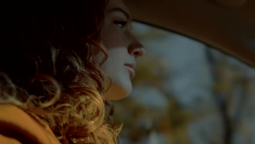 A woman drives along a tree lined road