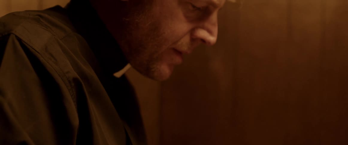 A priest is sitting at a table reading a bible