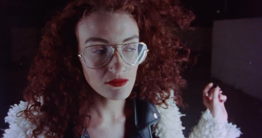 A woman is posing for the camera and wearing glasses