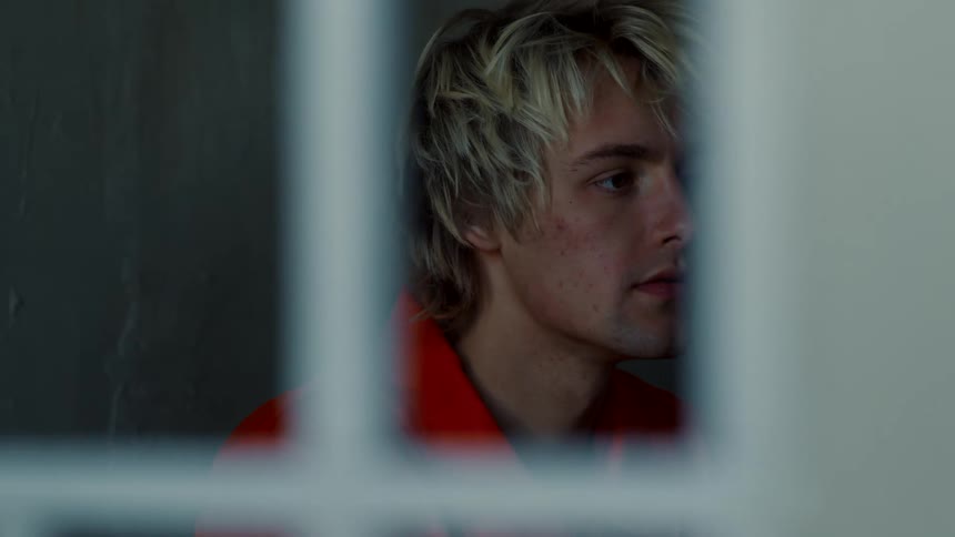 A man is sitting in his closed jail cell