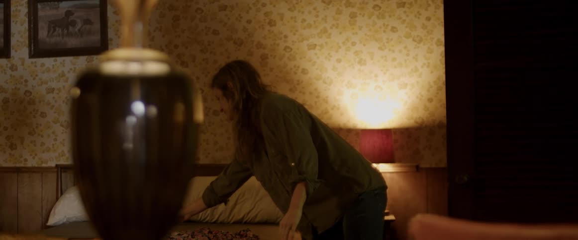 A woman lays a dress on the bed