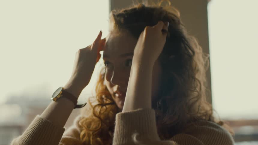Woman standing near windows styles her hair