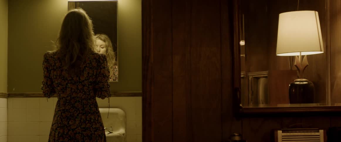 A woman is adjusting her hair in the mirror
