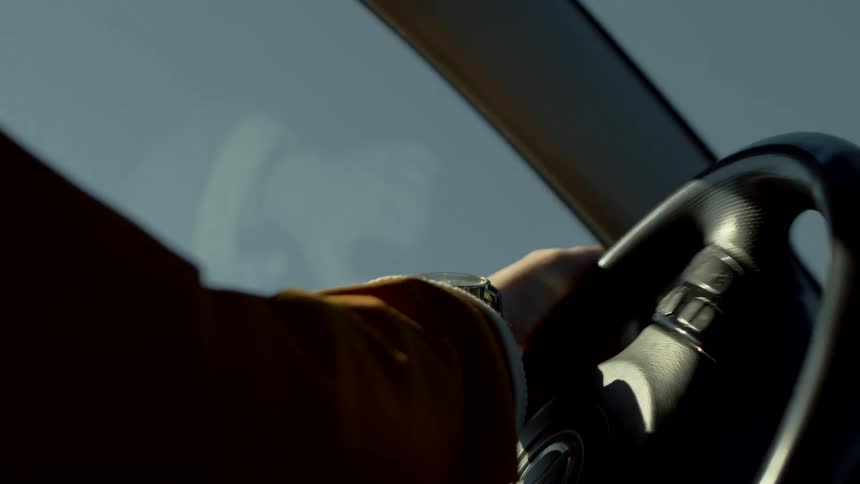 A man is quickly turning the steering wheel to whip the car around