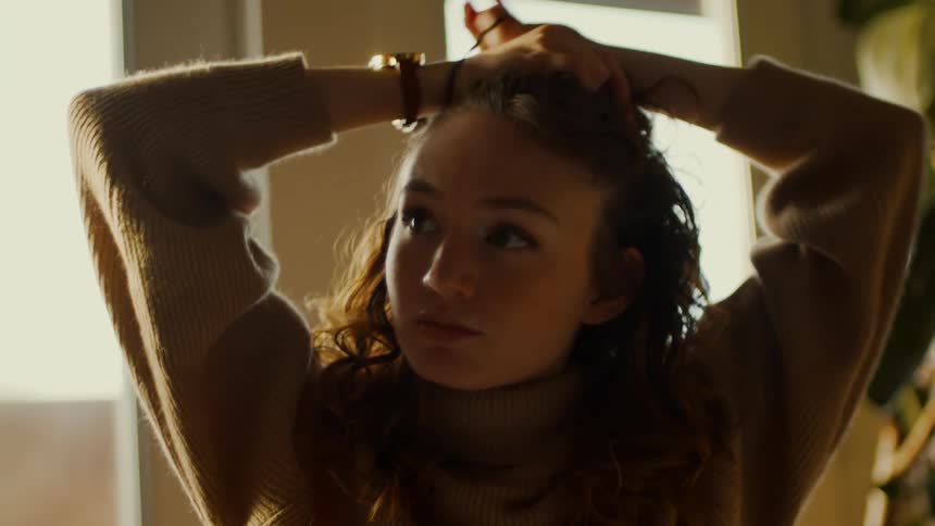 A woman tying up her hair in a room
