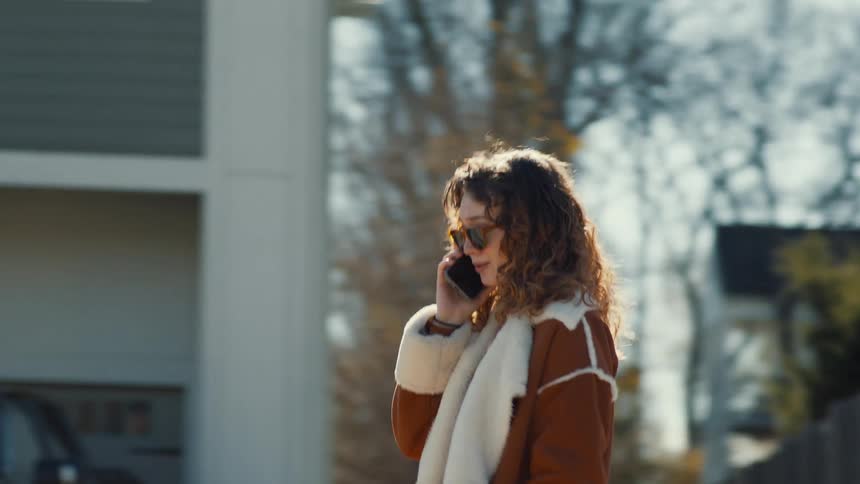 A woman walks down the street talking on a cell phone
