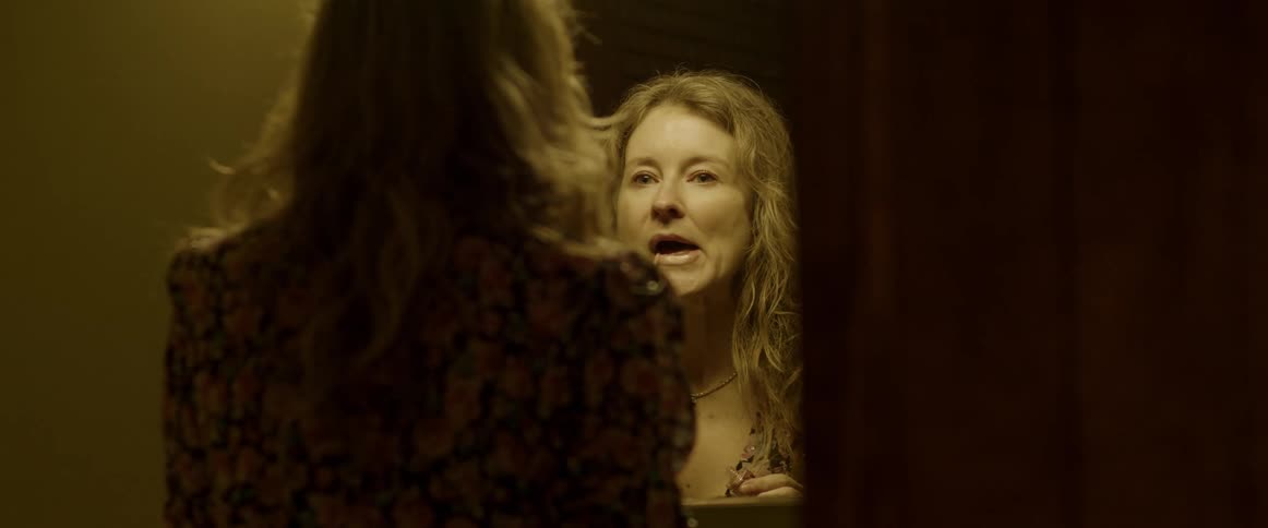 A woman is putting on makeup in the mirror
