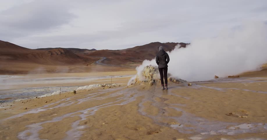 A person is standing on a field next to steam rising from the surface