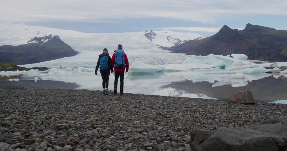 Two people walk towards the ice in the distance