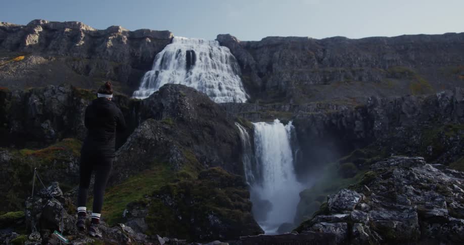 A person watches a waterfall from below