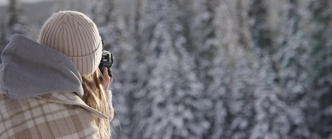 A woman is photographing the snow covered forest