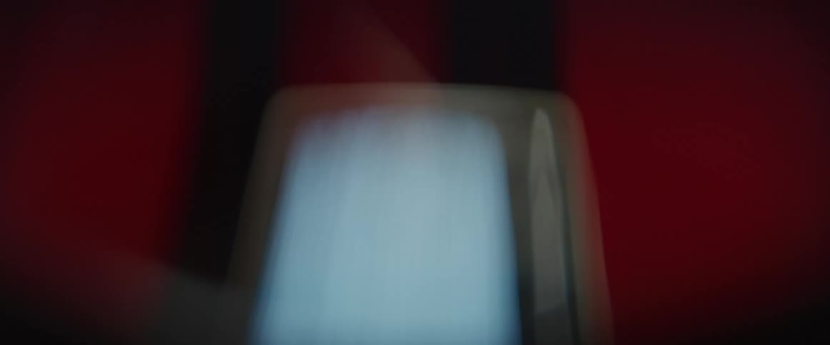 A television sitting on a shelf against a red wall plays static and blurs