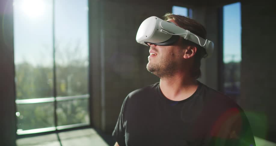 A man wearing virtual reality headsets in a room and looking around