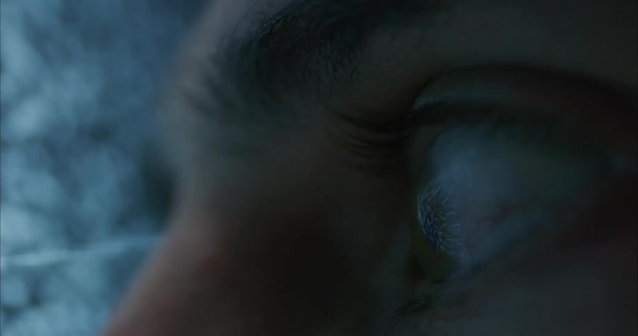 Close up of a persons eye darting back and forth as they look at a fuzzy television screen