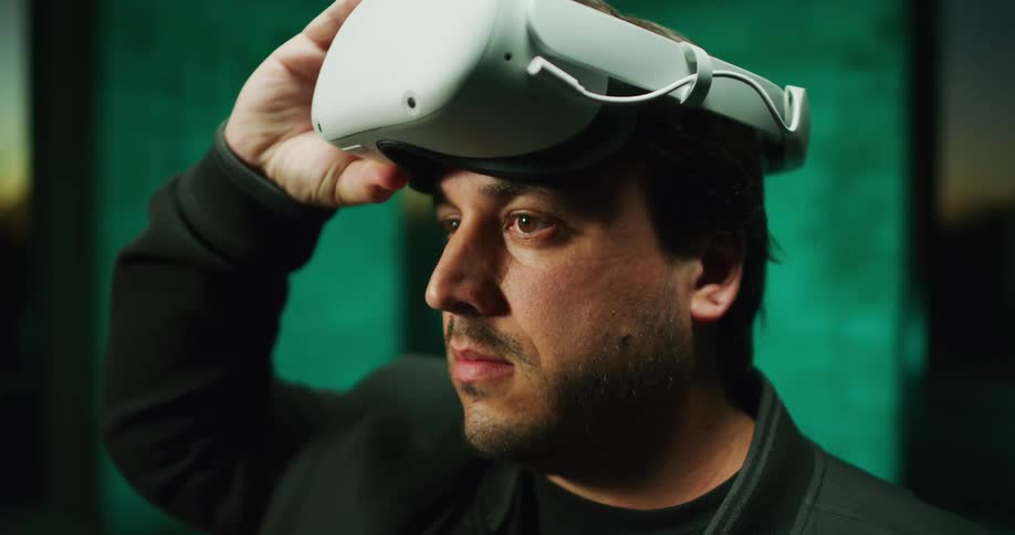 Man with brown hair and brown eyes takes off vr glasses and puts them back on with his hand