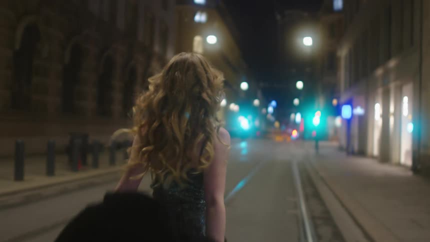 A woman walks down the middle of a road while removing her heavy coat