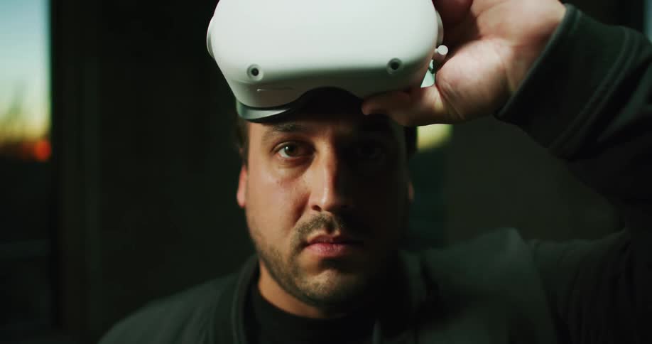 Closeup of a man wearing virtual reality headset and lifting them up