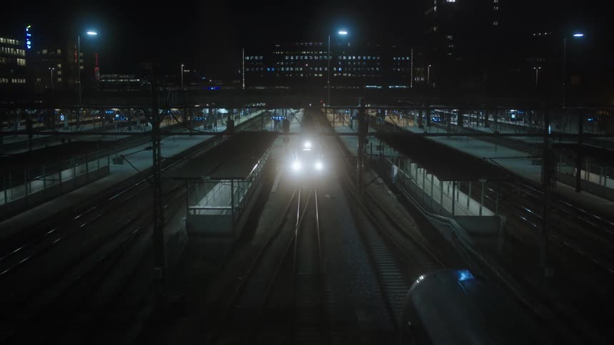 Public transit trains are moving through the city at night