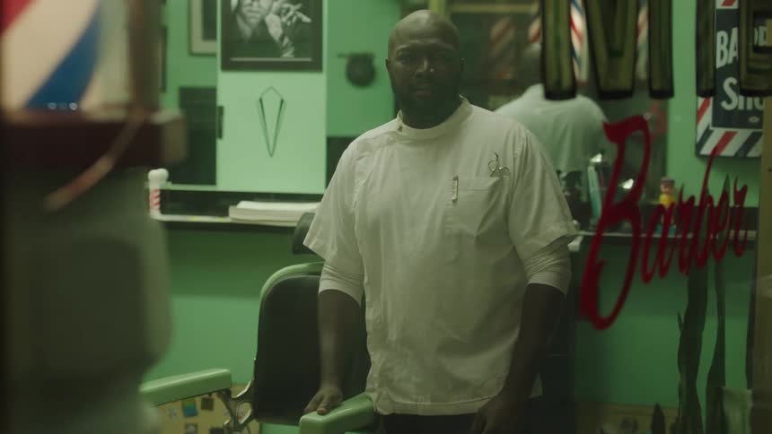 A man is standing inside of a barbershop