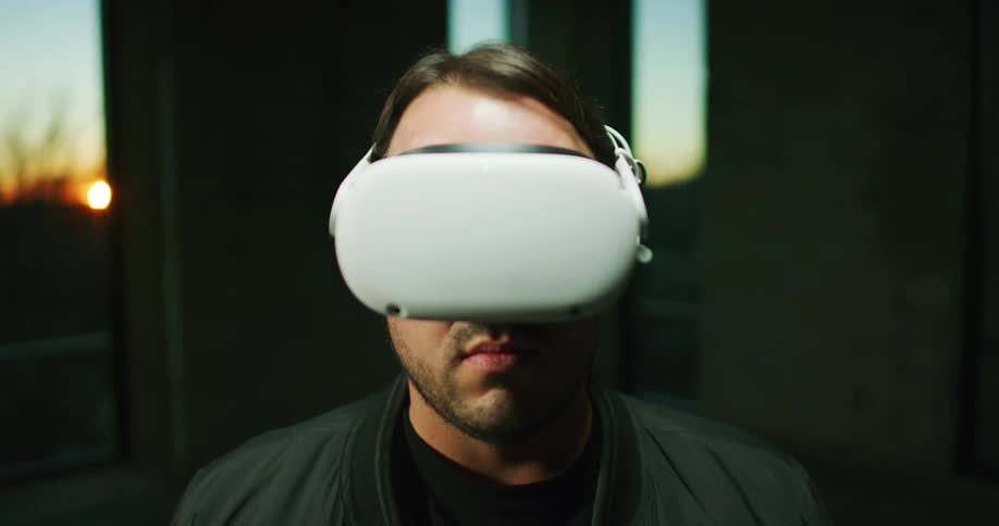 Man with black coat puts on white virtual reality at sunset
