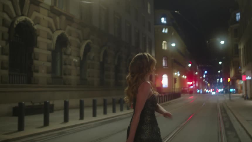 A woman walks down the street at night