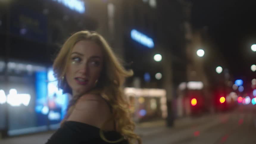 A woman dances in the street at night