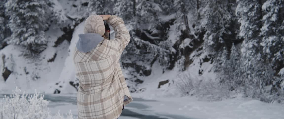 A photography takes a photograph of a snowy landscape