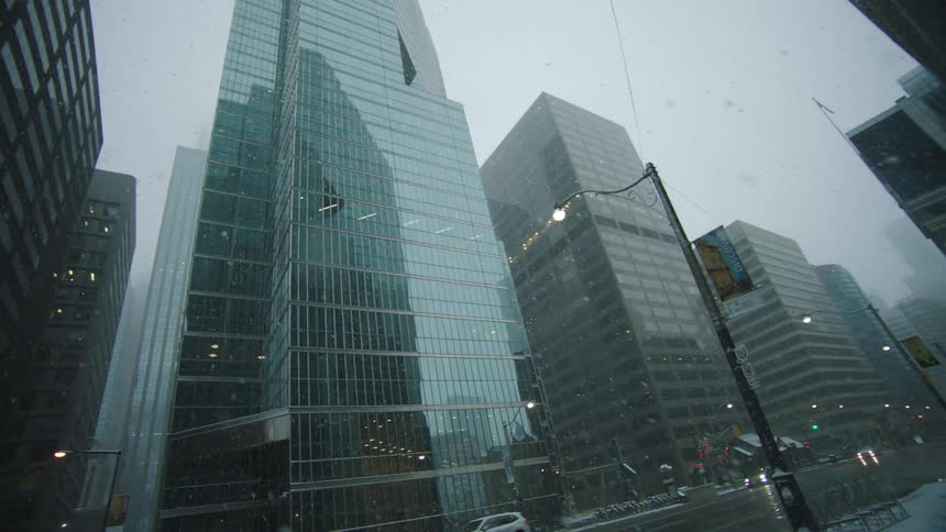 Cars drive down the city street as it snows