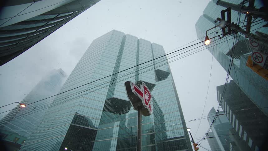 A pedestrian walks past the buildings as it snows