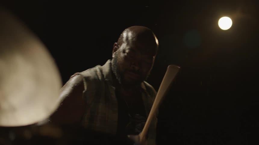 A man sweats and grimaces as he plays the drums